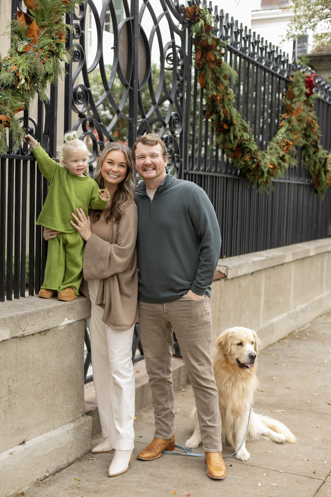 Family with golden retriever in front of a holiday-decorated Charleston gate
