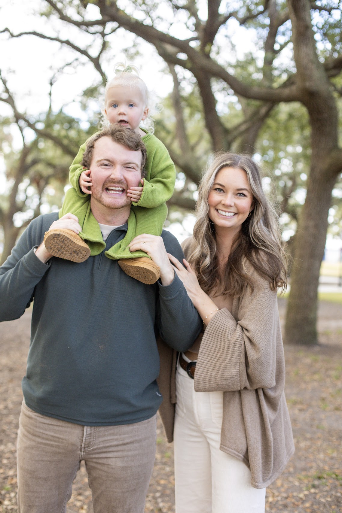 Family with toddler on dad's shoulders under Charleston oaks