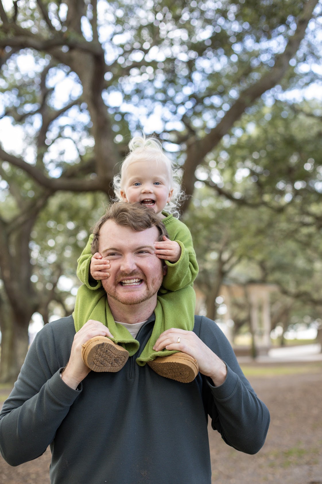 Dad with toddler on his shoulders under Charleston live oaks